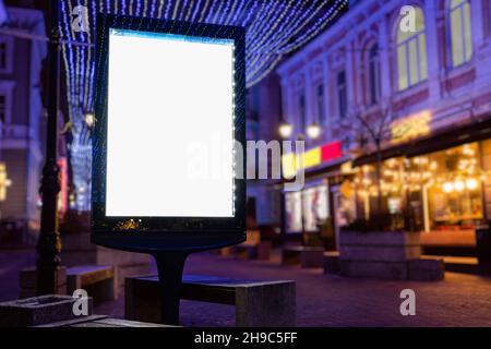 Blank weiß imitierte vertikale Plakatwand Straßenplakat auf einem weihnachtsbeleuchtung Stadt Hintergrund Stockfoto