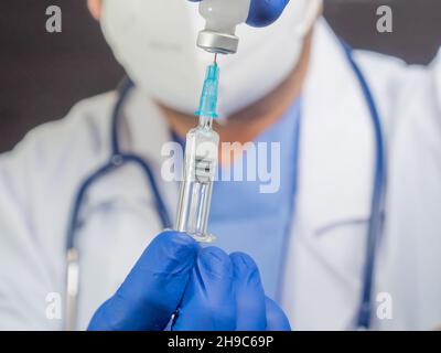 Nahaufnahme eines nicht erkennbaren Arztes mit Maske mit Spritze und Fläschchen. Stockfoto
