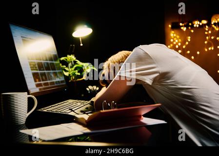 Frau, die am Arbeitsplatz auf dem Tisch schläft. Konzept der Überstundenarbeit. Arbeiten bei Nacht Stockfoto