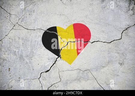 Das Symbol der belgischen Nationalflagge in Form eines Herzens auf einer rissigen Betonwand. Konzept. Stockfoto