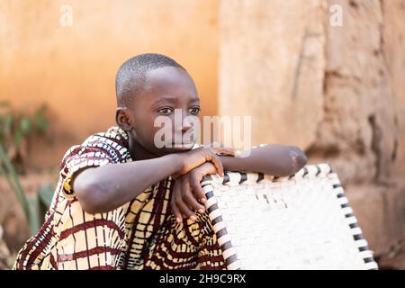 Süßer schwarzer afrikanischer Student, der in Gedanken verloren hatte, mit gekreuzten Armen, die sich auf einen Stuhl vor ihm lehnten Stockfoto