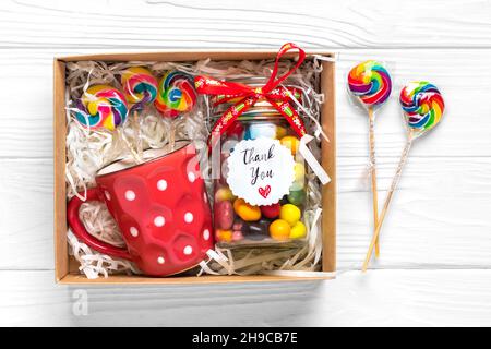 Handgemachtes Pflegepaket, saisonale Geschenkbox mit Süßigkeiten, Tasse auf weißem Tisch Personalisierter umweltfreundlicher Korb für Familie, Freunde, Mädchen für Danksagedanken Stockfoto