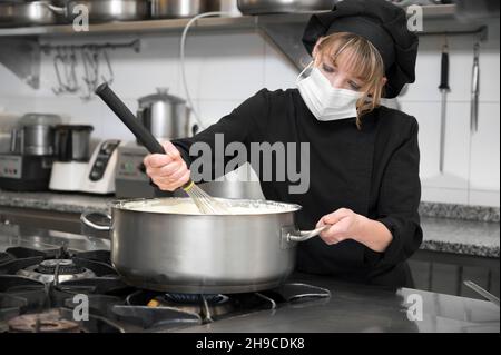 Konzept für Gesundheitsschutz, Sicherheit und Pandemie - Köchin trägt eine schützende Gesichtsmaske, während sie in der Restaurantküche arbeitet. Hochwertige Fotos Stockfoto