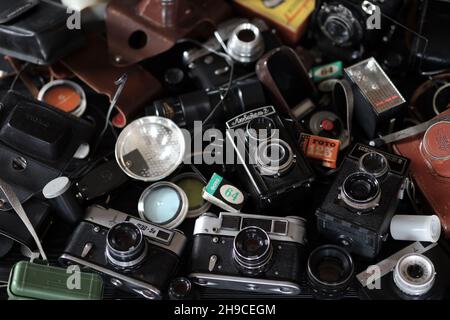 CHARKOV, UKRAINE - 27. APRIL 2021: Filmkameras und eine andere alte Retro-Fotoausrüstung auf schwarzem Holztisch in der Dunkelkammer des Fotografen. Foto Stockfoto