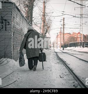 17th. November 2021, Russland, Tomsk, eine alte Frau gehen auf dem Rialway mit Taschen Stockfoto