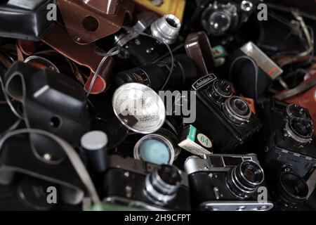 CHARKOV, UKRAINE - 27. APRIL 2021: Filmkameras und eine andere alte Retro-Fotoausrüstung auf schwarzem Holztisch in der Dunkelkammer des Fotografen. Foto Stockfoto
