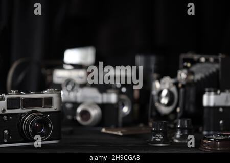 CHARKOV, UKRAINE - 27. APRIL 2021: Filmkameras und eine andere alte Retro-Fotoausrüstung auf schwarzem Holztisch in der Dunkelkammer des Fotografen. Foto Stockfoto