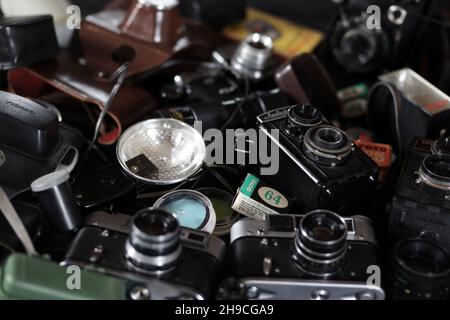 CHARKOV, UKRAINE - 27. APRIL 2021: Filmkameras und eine andere alte Retro-Fotoausrüstung auf schwarzem Holztisch in der Dunkelkammer des Fotografen. Foto Stockfoto