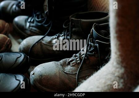 Viele alte Arbeitsstiefel stehen zusammen. Alte abgenutzte Baustiefel der Arbeiter. Hintergrund. Echte Szene. Schaltschuhe. Stockfoto