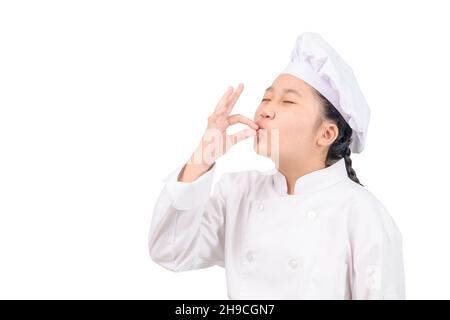 Niedlichen Koch Mädchen zeigt Zeichen für lecker. Kinderkoch in weißer Uniform mit perfektem Schild. Seriös zufrieden bärtiger Koch, Koch oder Bäcker gestikulieren excell Stockfoto