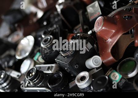 CHARKOV, UKRAINE - 27. APRIL 2021: Filmkameras und eine andere alte Retro-Fotoausrüstung auf schwarzem Holztisch in der Dunkelkammer des Fotografen. Foto Stockfoto