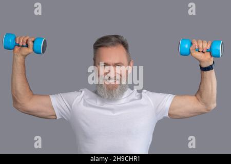 Lächelnder Mann mit Hanteln beim Training Stockfoto