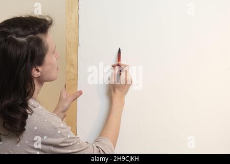 Der Künstler zeichnet mit Bleistift auf eine weiße Leinwand. Blick hinter die Schulter. Zeichnen mit Aquarellen in einem Home Art Studio. Stockfoto