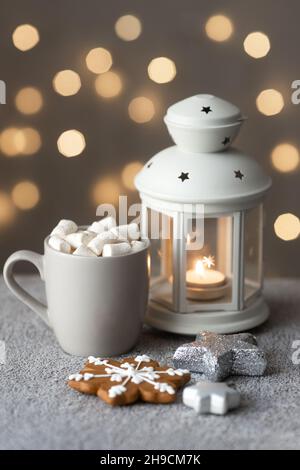 Gemütlicher Winterurlaub Hintergrund mit Lebkuchenkuchen auf dem Tisch, Kerzen und einer Tasse Kaffee mit Marshallows Stockfoto