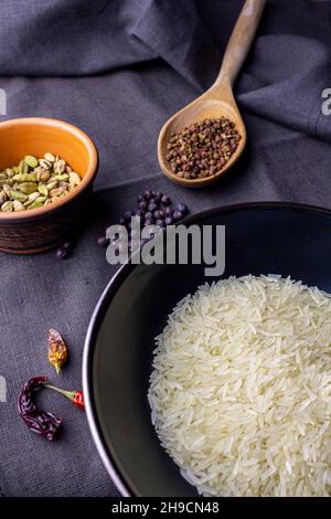 Reisschüssel mit Kardamon, Chili und sichuan-Papier auf dunklem Tuch mit Wacholderbeere Stockfoto