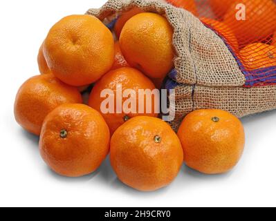 Reife orangefarbene Mandarinen oder Mandarinen, die in einem Netzbeutel auf weißem Hintergrund liegen, aus der Nähe Stockfoto