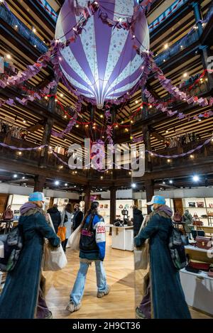 London, Großbritannien. 6. Dezember 2021. Ein allgemeiner Blick auf die Weihnachtsdekoration im Kaufhaus Liberty in Form eines riesigen aufgehängten Heißluftballons, der die Botschaft „mit Liebe ausgewählt, mit Magie geprägt“ trägt. Vor dem Hintergrund der steigenden Anzahl von Omicron-Koffern sind für die Käufer Gesichtsbezüge erforderlich, da sich die Einzelhändler auf die geschäftige Weihnachtszeit vorbereiten. Kredit: Stephen Chung / Alamy Live Nachrichten Stockfoto