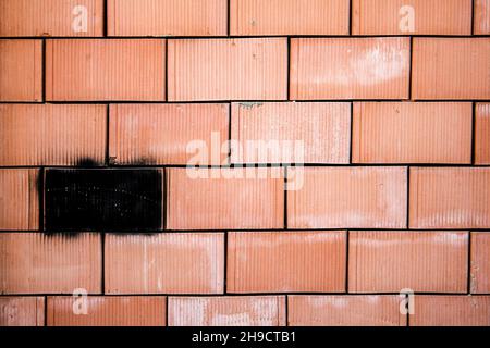 Rote Ziegelwand mit einem schwarz lackierten Element Stockfoto