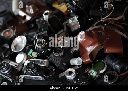 CHARKOV, UKRAINE - 27. APRIL 2021: Filmkameras und eine andere alte Retro-Fotoausrüstung auf schwarzem Holztisch in der Dunkelkammer des Fotografen. Foto Stockfoto