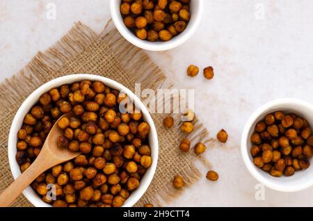 Geröstete Kichererbsen in weißen Schalen und einem Holzlöffel. Stockfoto