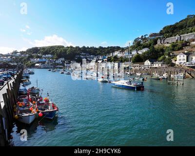 Der Hafen in Looe Cornwall zeigt die Wohnungen auf den Hügeln, die die vielen auf dem Wasser verankerten Boote und die Brücke umgeben Stockfoto