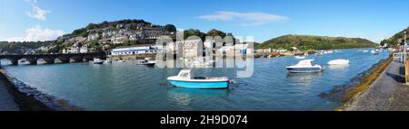 Der Hafen in Looe Cornwall zeigt die Wohnungen auf den Hügeln, die die vielen auf dem Wasser verankerten Boote und die Brücke umgeben Stockfoto