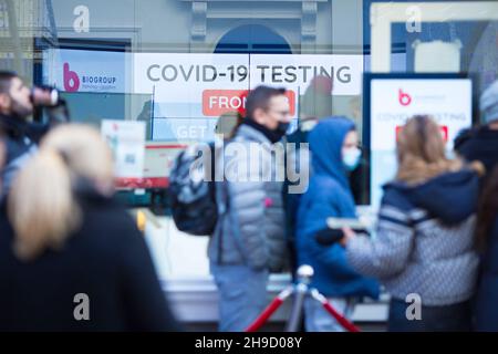 Eine Werbetafel wird in einer Klinik gesehen, während sich die Menschen im Zentrum von London davor anstellen. Stockfoto