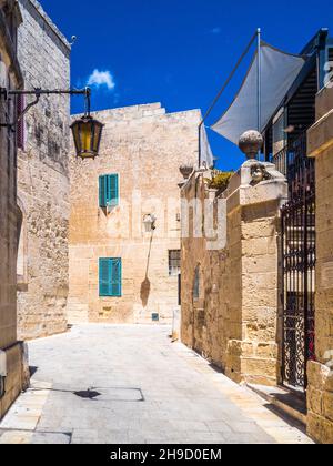 Enge Straße in Mdina, der alten Hauptstadt von Malta, unter klarem blauen Himmel. Stockfoto