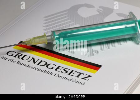 Symbolbild zum Thema Grundrechte, Deutschland: Das Grundgesetz mit einer Unterspritze als Symbol für die Corona-Impfung Stockfoto