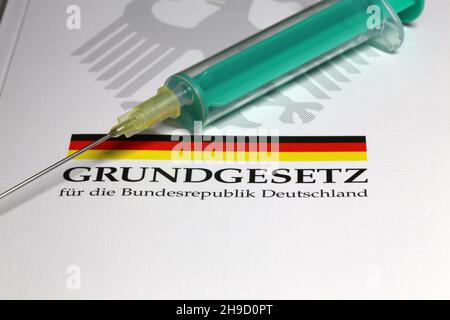 Symbolbild zum Thema Grundrechte, Deutschland: Das Grundgesetz mit einer Unterspritze als Symbol für die Corona-Impfung Stockfoto