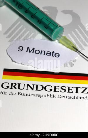 Symbolbild zum Thema Grundrechte, Deutschland: Das Grundgesetz mit einer Unterspritze als Symbol für die Corona-Impfung Stockfoto