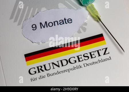 Symbolbild zum Thema Grundrechte, Deutschland: Das Grundgesetz mit einer Unterspritze als Symbol für die Corona-Impfung Stockfoto