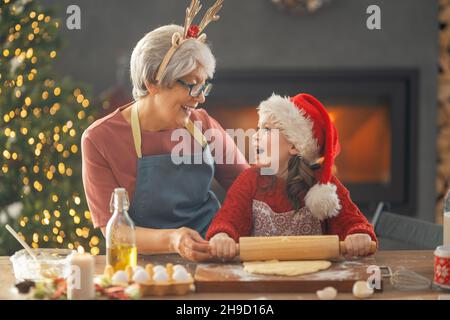 Frohe Weihnachten und frohe Feiertage. Familienzubereitung Urlaub Essen. Oma und Enkelin kochen Plätzchen. Stockfoto