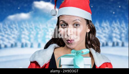 Porträt einer jungen Frau in santa Hut und warme Kleidung puckern während halten Geschenk Stockfoto
