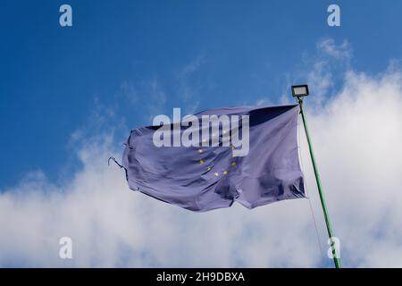 Die Flagge der Europäischen Union weht im Wind in Richtung des wolkigen blauen Himmels an einem sonnigen Tag Stockfoto