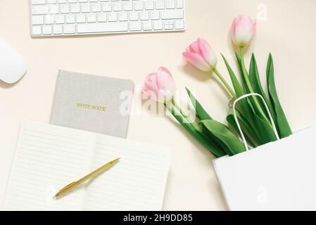 Tulpen, Geschenkbox und Kaffee auf beigem Hintergrund. Flach liegend. 8. März, Internationaler Frauentag. Valentinstag. Arbeitsplatz des Bloggers Stockfoto