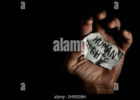 Ein Mann hat ein Stück Papier in der Hand mit dem darin geschriebenen Text Menschenrechte Stockfoto