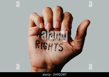 Nahaufnahme der Hand eines Mannes mit dem darin geschriebenen Text Menschenrechte auf einem cremefarbenen Hintergrund Stockfoto