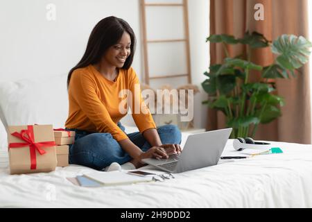 Afrikanische Frau Mit Laptop Sitzen In Der Nähe Geschenke Boxen Im Schlafzimmer Stockfoto