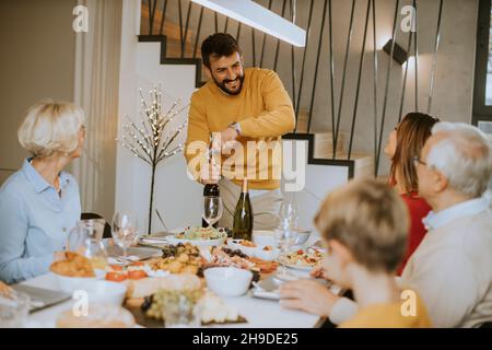 Hübscher junger Mann, der zu Hause eine Flasche Rotwein öffnet Stockfoto