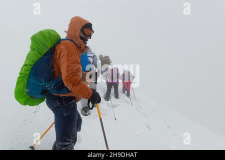 Gruppe von Wanderern, die versuchen, im tiefen Schnee in den Winterbergen bei schlechtem Wetter und starkem Schneefall zu überleben. Sicherheit in den Winterbergen Konzept Stockfoto