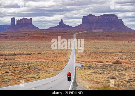 Forrest Gump Point und einsamer Radler auf dem Highway 163 Scenic Drive, gerade Straße, die nach Monument Valley, San Juan County, Utah, USA, führt Stockfoto