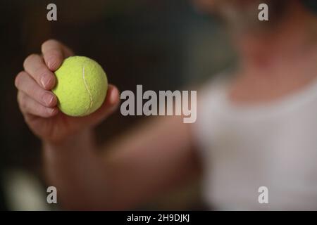 Gelber Tennisball in der Hand des Tennisspielers Stockfoto