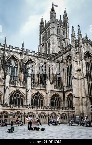 Ein Straßenkünstler spielt von Bath Abbey. Bath Abbey ist eine Pfarrkirche der Church of England und ehemaliges Benediktinerkloster in Bath, Somerset. Stockfoto