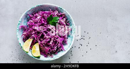 Frischer roher Lila Salat in Keramik Schüssel Chinakohl auf grauem Beton alten Hintergrund. Draufsicht. Stockfoto