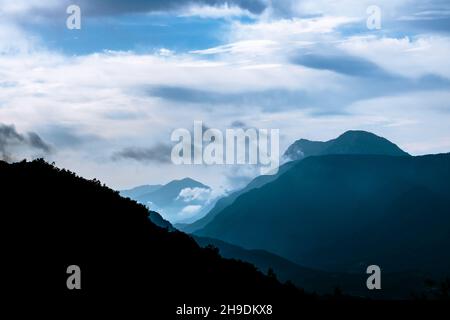 Hills Silhouetten. Wolkiger Himmel und Silhouetten in den Bergen am Morgen. Hügel und Täler bei nebligen Sonnenaufgängen. Schwierigkeiten Konzept Idee Hintergrund Foto. Stockfoto