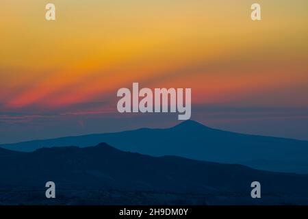 Mountain Peak. Berggipfel und Silhouetten bei Sonnenuntergang mit dramatischen Wolken. Hintergrundfoto bei Sonnenuntergang, Dämmerung oder Dämmerung Stockfoto