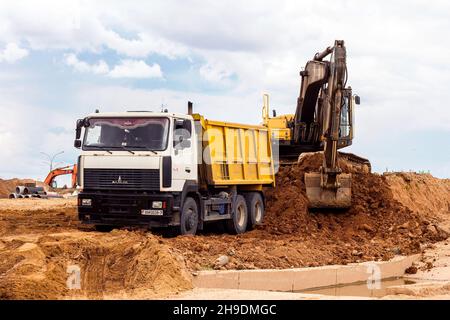 MINSK, WEISSRUSSLAND - 2. Juli 2021: Schwerer Industriebagger in hellgelb, der auf der Baustelle in der Stadt arbeitet. Stockfoto