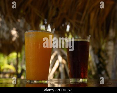 Das Foto zeigt Coca Cola Erfrischungen und Passionsfruchtsaft. Foto aufgenommen in der Bar auf einer karibischen Insel. Der Strand und die Meereslinie sind in der sichtbar Stockfoto