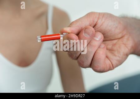 Der Arzt hält kleine Ampullen in den Händen. Nahaufnahme einer kleinen Ampulle mit einem Impfstoff in der Hand des Arztes. Reagenzglas für Allergietest halten. Allergietests Stockfoto